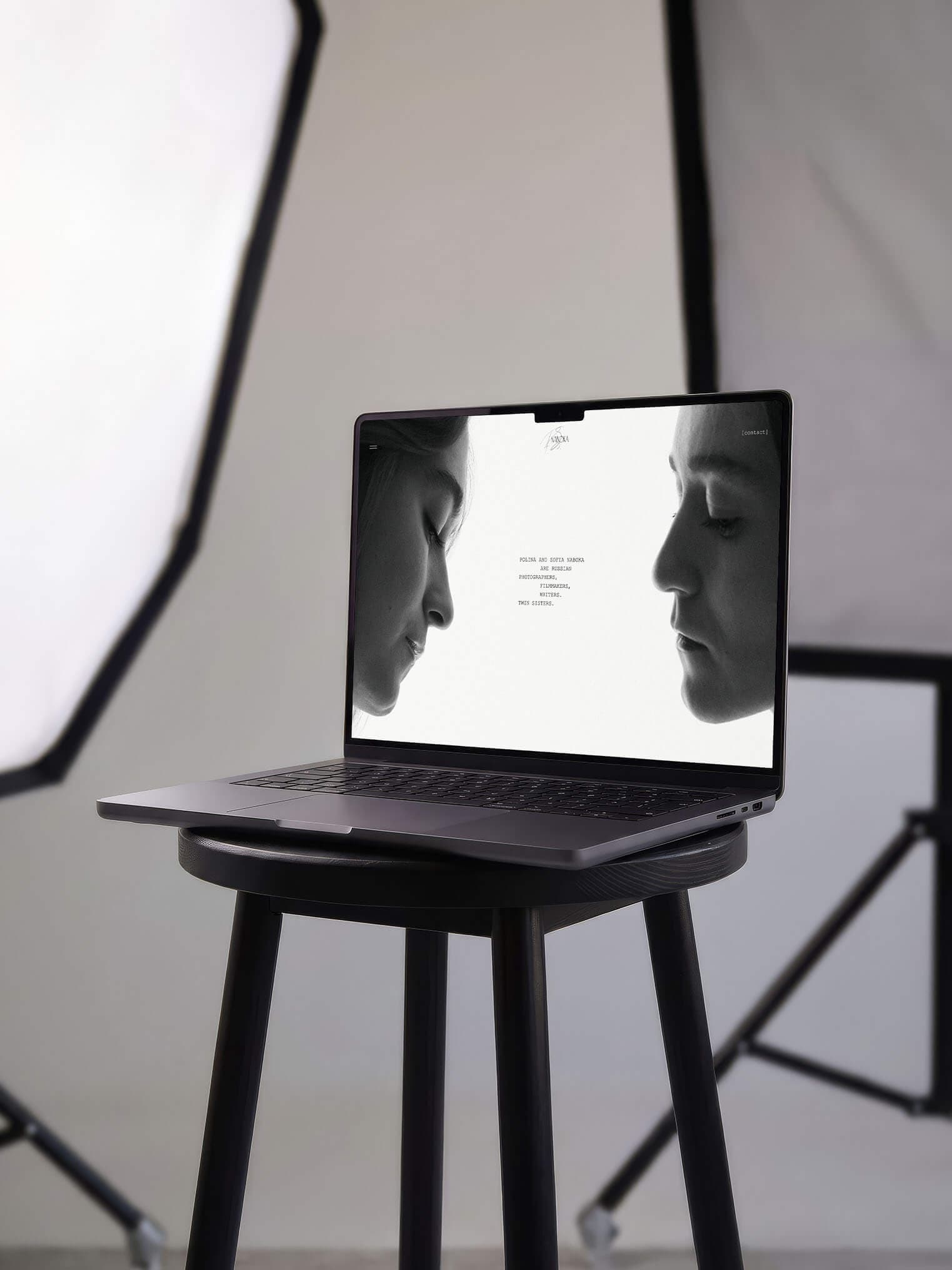 Laptop showing the Naboka photography website on a stool